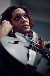 Portrait eines Musikers mit seiner Gitarre