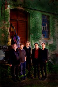 fünf Musiker stehen vor einer alten Hausfassade